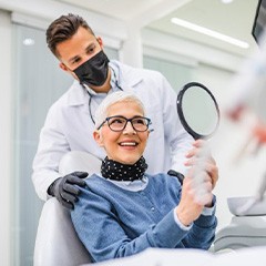 a patient checking her smile with a mirror