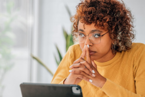 Woman sitting at computer trying to decide between braces and clear aligners