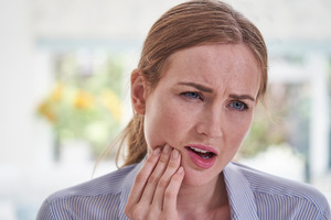 Close-up of woman rubbing her jaw in pain